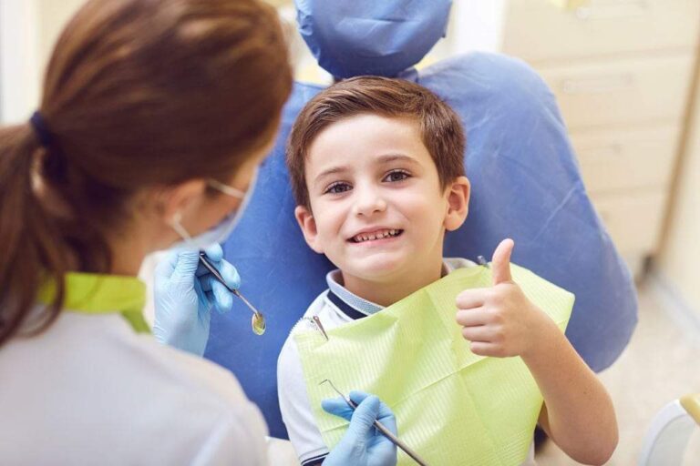 A child gives a thumbs up to show they are enjoying their pediatric dentistry appointment.